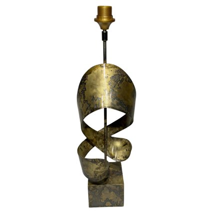 Indická kovová lampa s jemnými zlatavými odlesky a zdobením připomínajícím elegantně vinuté kovové pásy.