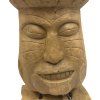Tiki totem v podobě hlavy, precizně vyřezaný z teakového dřeva, umístěný na podstavci.