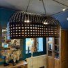 Velká závěsná lampa tvořená mosaznými kovovými proužky v proplétaném designu, voskovaná pro elegantní vzhled, ideální pro umístění nad stůl.